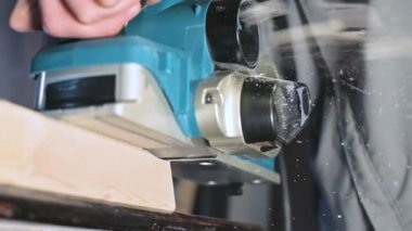Bir ev atölyesinde bir elektrik uçağı ile çalışan bir marangozlar el yakın çekim. Yavaş hareket ahşap parçaları bitirme