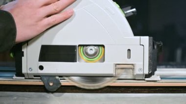 Büyük yakın çekim. Elektrikli dairesel testere ile ahşap tahta kesme bir marangoz. Toz parçacıklarının ve testere bıçağının yavaş hareketi