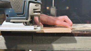 Erkek marangozlar eller ev atölyesinde bir elektrikli yapboz olarak çalışır. Yavaş hareket halindeki ahşap parçaları kesme