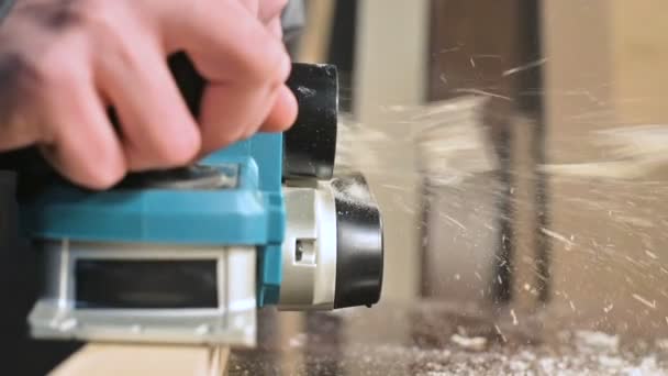 Big close-up. A carpenter cutting a wooden board with an electric plane. Slow motion of dust particles and saw blade — Stock Video