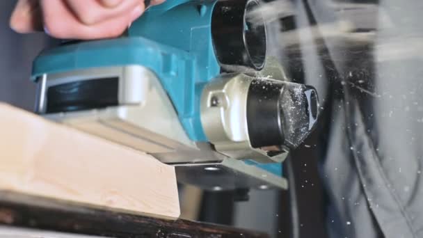 Close-up de uma mão carpinteiros trabalhando com um avião elétrico em uma oficina em casa. Acabamento de peças de madeira em câmera lenta — Vídeo de Stock