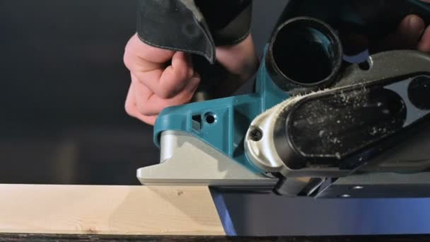 Nahaufnahme einer Tischlerhand, die in einer heimischen Werkstatt mit einem elektrischen Flugzeug arbeitet. Holzteile in Zeitlupe veredeln — Stockvideo