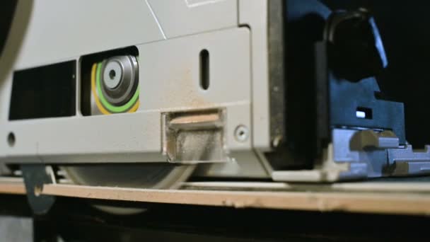 Big close-up. A carpenter cutting a wooden board with an electric circular saw. Slow motion of dust particles and saw blade — Stock Video