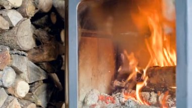 Bir ev yapımı modern Ocak refrakter cam arka ahşap büyük bir yığını yanında gün boyunca yanan odun yakın çekim. Çevre dostu enerji