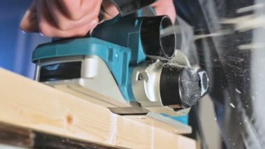 Bir ev atölyesinde bir elektrik uçağı ile çalışan bir marangozlar el yakın çekim. Yavaş hareket ahşap parçaları bitirme