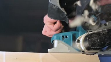 Bir ev atölyesinde bir elektrik uçağı ile çalışan bir marangozlar el yakın çekim. Yavaş hareket ahşap parçaları bitirme