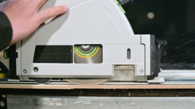 Büyük yakın çekim. Elektrikli dairesel testere ile ahşap tahta kesme bir marangoz. Toz parçacıklarının ve testere bıçağının yavaş hareketi