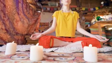 Gevşek giysiler içinde güzel bir genç kız mumlar ile çevrili bir Lotus pozisyonda beyaz bir kürk cilt üzerinde bir zanaat odasında oturur. Meditasyon ruhsal büyüme ve bakım kendi sağlık için