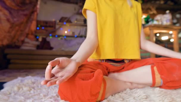 Κοντινό σημείο του σώματος ενός νεαρού κοριτσιού στη θέση του λωτού που κάθεται σε μια αίθουσα χειροτεχνίας σε ένα λευκό δέρμα γούνας που περιβάλλεται από κεριά. Διαλογισμός πνευματική ανάπτυξη και φροντίδα για την υγεία σας — Αρχείο Βίντεο