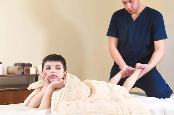 Petit garçon ennuyé patient à la réception à une masseuse professionnelle. Thérapie de massage des pieds — Photo