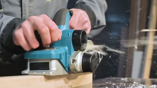 Grote close-up. Een timmerman snijden van een houten bord met een elektrisch vliegtuig. Slow Motion van stofdeeltjes en zaagblad — Stockvideo