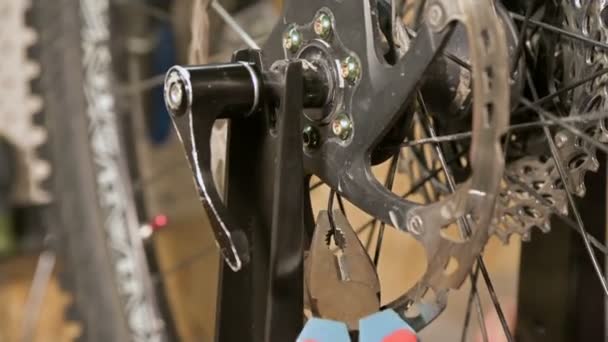 Крупный план мастера, демонтирующего изогнутую вязальную спицу на стойке технического обслуживания велосипедных колес — стоковое видео