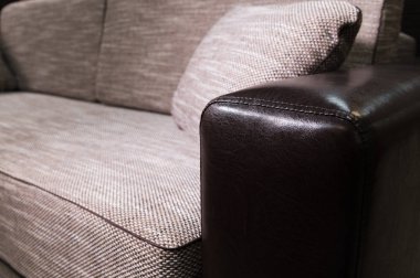 Siyah deri kolçak ile yakın çekim elemanı Bej gri kanepe. Minderli birinci sınıf mobilyalar