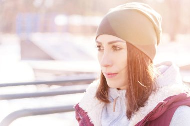 Eldiven ve güneşli bir Kışın açık havada egzersiz bahçesi yanında sıcak bir yelek ile şapkalı bir kız atlet portresi