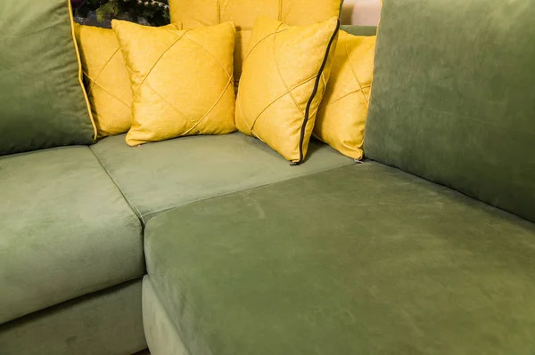 Крупный план зеленый угловой диван с желтыми подушками. Текстиль новая мебель современный дизайн — стоковое фото