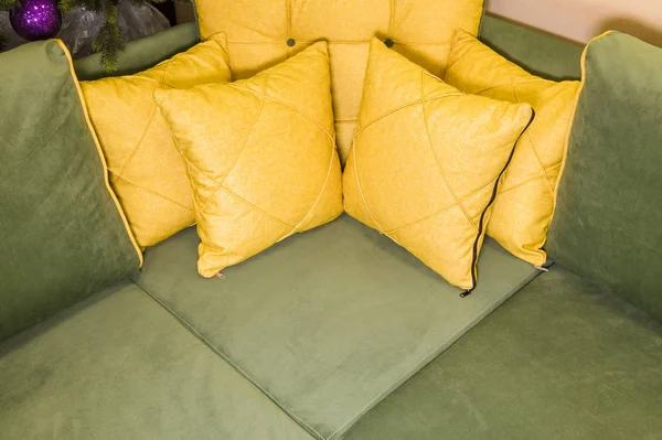 Close-up green corner sofa with yellow pillows. Textile new furniture modern design