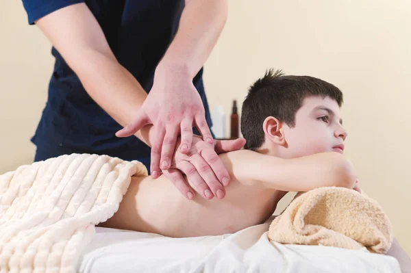 Zrelaksowany mały chłopiec na recepcji w kręgarza. Zabieg masażu Wellness — Zdjęcie stockowe