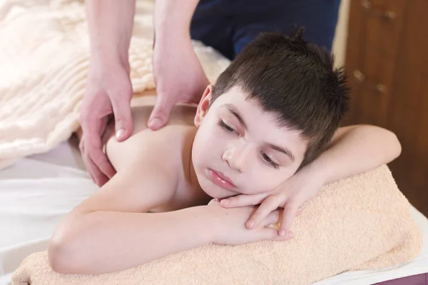 A little boy relaxes from a therapeutic massage. Male massage therapist makes a medical massage to the back of a child — Stock Photo, Image