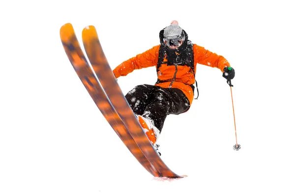 Le skieur sportif en costume orange noir fait le tour à l'arrière des skis. vraie photo réalisée dans les montagnes isolées sur fond blanc — Photo