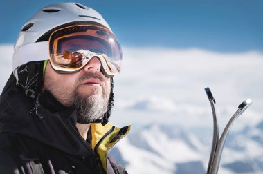 Maskeli Kafkas dağlarının yansıması olan bir kayak merkezinin karla kaplı dağlarına kask lı ve kar maskeli yakın çekim atlet kayakçı