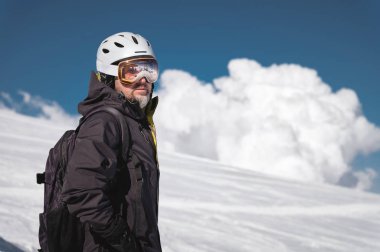 Maskeli Kafkas dağlarının yansıması olan bir kayak merkezinin karla kaplı dağlarına kask lı ve kar maskeli yakın çekim atlet kayakçı