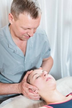 İçgüdüsel doktor genç bir kızın kafatasının elle düzenlenmesiyle meşgul. Alternatif tıp. Sağlığı Önleme Kavramı