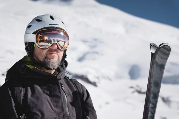 Esquiador atleta close-up em capacete e máscara de esqui contra as montanhas cobertas de neve de uma estância de esqui com um reflexo das montanhas caucasianas na máscara — Fotografia de Stock