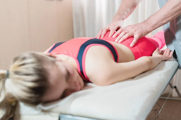 Girls spine base editing by a male physiotherapist of visceral massage. The hands of the doctor set and knead the tailbone of the patient — Stock Photo, Image