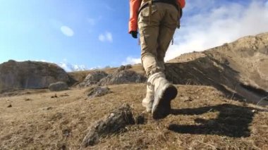 Bir kız gezgin bacakları güneşli bir günde karla kaplı zirveleri bir arka plan üzerinde yokuş yukarı gitmek