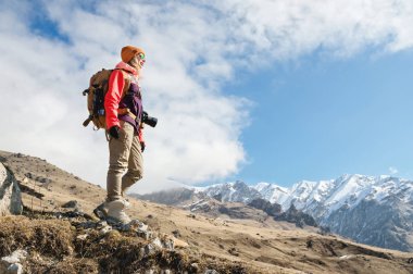Güneş gözlüğü bir kamera ve karla kaplı Kafkas dağlarının arka plan karşı bir şapka ile fotoğrafçı hipster turist kız Portresi. Fotoğraf seyahat konsepti