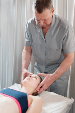 İçgüdüsel doktor genç bir kızın kafatasının elle düzenlenmesiyle meşgul. Alternatif tıp. Sağlığı Önleme Kavramı