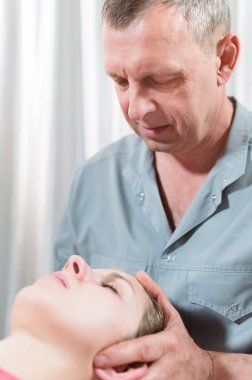 İçgüdüsel doktor genç bir kızın kafatasının elle düzenlenmesiyle meşgul. Alternatif tıp. Sağlığı Önleme Kavramı