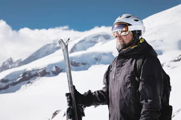 Atleta ritratto sciatore in casco e maschera da sci contro le montagne innevate di una stazione sciistica con un riflesso delle montagne caucasiche in maschera — Foto Stock