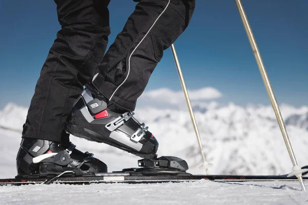 Close-up dos atletas esquiadores pé em botas de esqui sobe para os esquis contra o fundo das montanhas do Cáucaso cobertas de neve em um dia ensolarado. Conceito de esportes de inverno — Fotografia de Stock