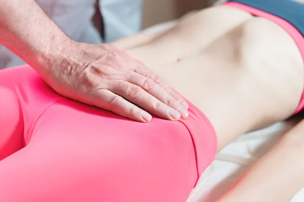 Mannelijke handmatige viscerale therapeut masseur behandelt een jonge vrouwelijke patiënt. Externe opwarming van de baarmoeder met de energie van de handen — Stockfoto