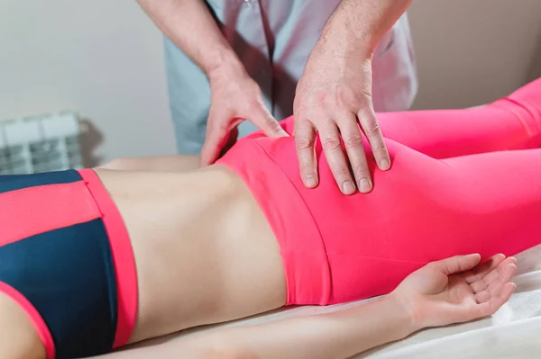Close-up of a young girls spine base editing by a male physiotherapist of visceral massage. The hands of the doctor set and knead the tailbone of the patient — Stock Photo, Image