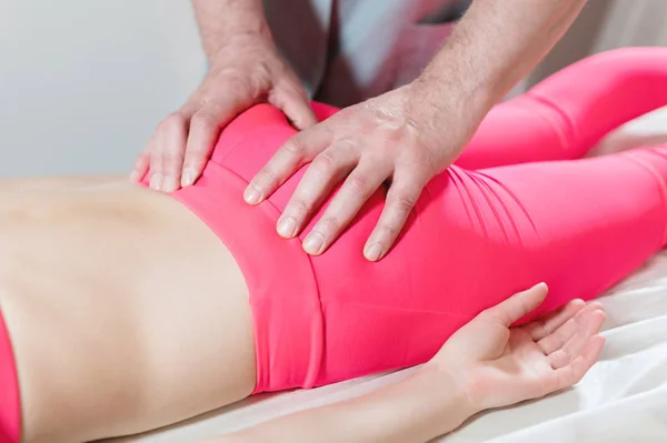 Close-up of a young girls spine base editing by a male physiotherapist of visceral massage. The hands of the doctor set and knead the tailbone of the patient — Stock Photo, Image