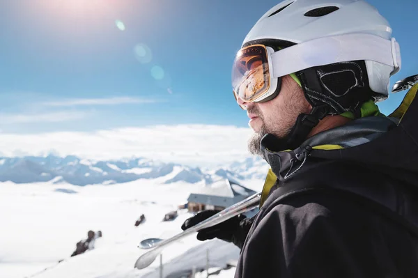 Acercamiento atleta esquiador en casco y pasamontañas contra las montañas nevadas de una estación de esquí con un reflejo de las montañas caucásicas en la máscara —  Fotos de Stock