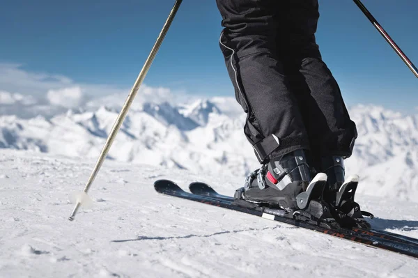 Close-up dos atletas esquiadores pé em botas de esqui sobe para os esquis contra o fundo das montanhas do Cáucaso cobertas de neve em um dia ensolarado. Conceito de esportes de inverno — Fotografia de Stock