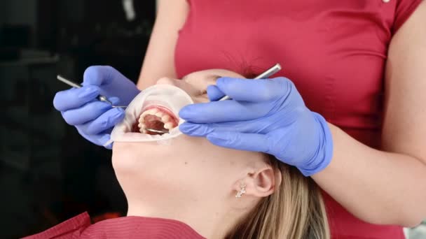 여성 전문 치과 의사가 사무실에서 조직학적 현미경을 가진 여성 환자를 검사합니다. 스타모톨로지스트 직업 개념 — 비디오