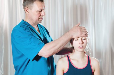 İçgüdüsel doktor genç bir kızın kafatasının elle düzenlenmesiyle meşgul. Alternatif tıp. Sağlığı Önleme Kavramı