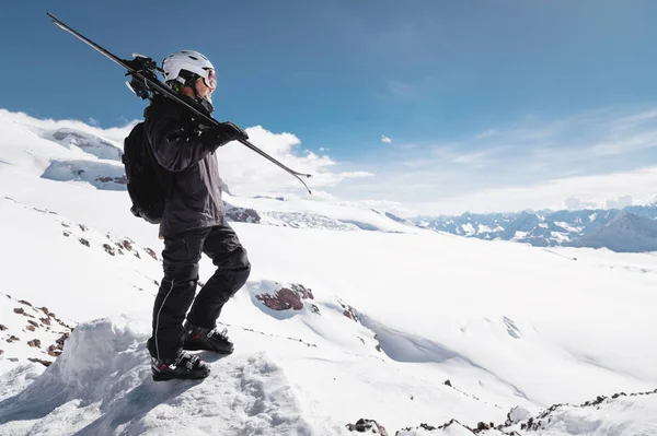 Růst portrétní vousatý samec lyžoval na pozadí zasněžené kavkazského pohoří. Dospělý muž, který nosí na rameni lyžařskou Googles masku a helmu, vypadá jako hory. Koncepce lyžařského letoviska — Stock fotografie