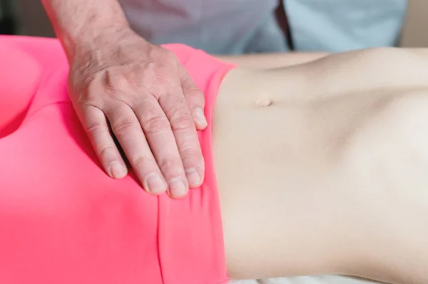 Mannelijke handmatige viscerale therapeut masseur behandelt een jonge vrouwelijke patiënt. Externe opwarming van de baarmoeder met de energie van de handen — Stockfoto