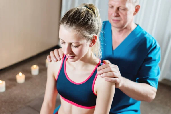 男性の手動内臓セラピストマッサージ師は若い女性患者を扱う。肩と前腕の診断 — ストック写真