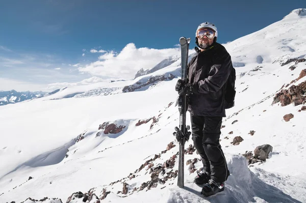 Retrato atleta esquiador em capacete e máscara de esqui contra as montanhas cobertas de neve de uma estância de esqui com um reflexo das montanhas caucasianas na máscara — Fotografia de Stock