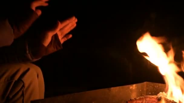Közeli, teljes sötétségben egy nő felmelegíti a kezét egy nyitott tüzet. Női pálmák a tűz éjjel — Stock videók