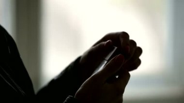 Kadın ellerinin siluetinin yakın çekimbir paket sigara açılması ve oradan bir sigara almak. Düşük anahtar sigaranın zarar acımasız kavramı