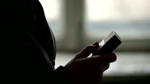 Close-up of the silhouette of female hands opening a pack of cigarettes and getting a cigarette from there. The grim concept of the harm of smoking in a low key — Stock Video