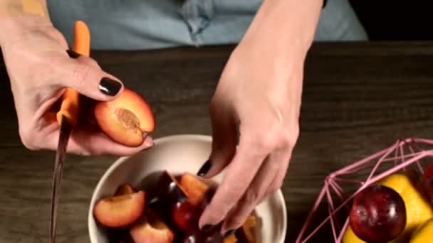 Zbliżenie kobiece ręce w kuchni domowej cięcia świeżych jagód z nożem śliwki i biorąc kość z nich obok koszyka cytryn. Koncepcja zdrowej żywności i witamin — Wideo stockowe