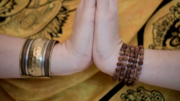 Close-up of womens hands in bracelets in a gesture of namaste and namaskar religious greeting. The girl in an authentic scarf practicing meditation standing in the studio on a white background — Stock Video